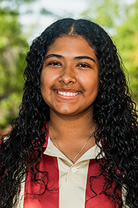 smiling female student with long, curly brown hair 