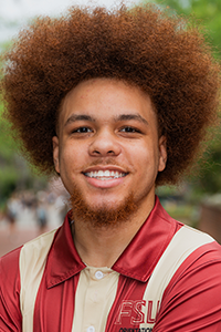 smiling male student with a large fro, dark brown fading to light brown ombre fro