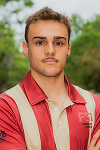 stoic male student with short, close-cropped brown hair with blonde tips and a moustache and stubble