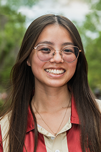 smiling female student with long brown hair and glasses with a thin metal frame