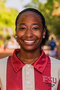 smiling female student with ball-shaped silver stud earrings and brown hair pulled back into a pouf at the base of her neck