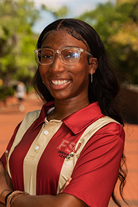 smiling femaile student with glasses with a clear plastic frame and long straight brown hair
