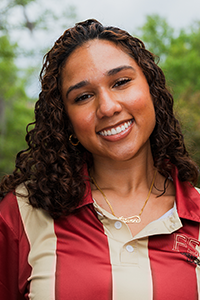 smiling female student with shoulder-length curly brown hair and head cocked to the right