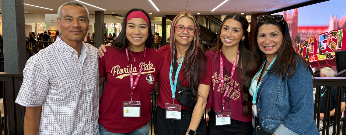 A group of five people smiling and posing for a photo, with some wearing Florida State-themed clothing.