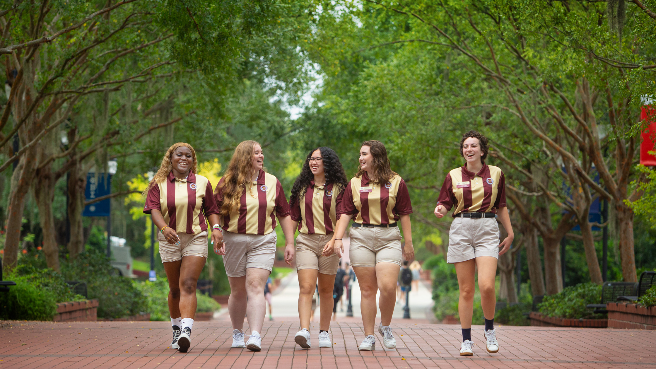 5 orientation leaders in striped shirts walk on legacy walk