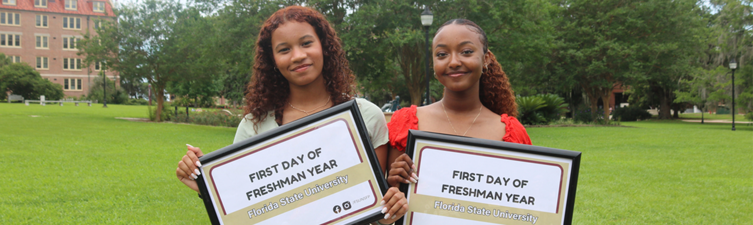 Two students holding up signs during First Day Photos